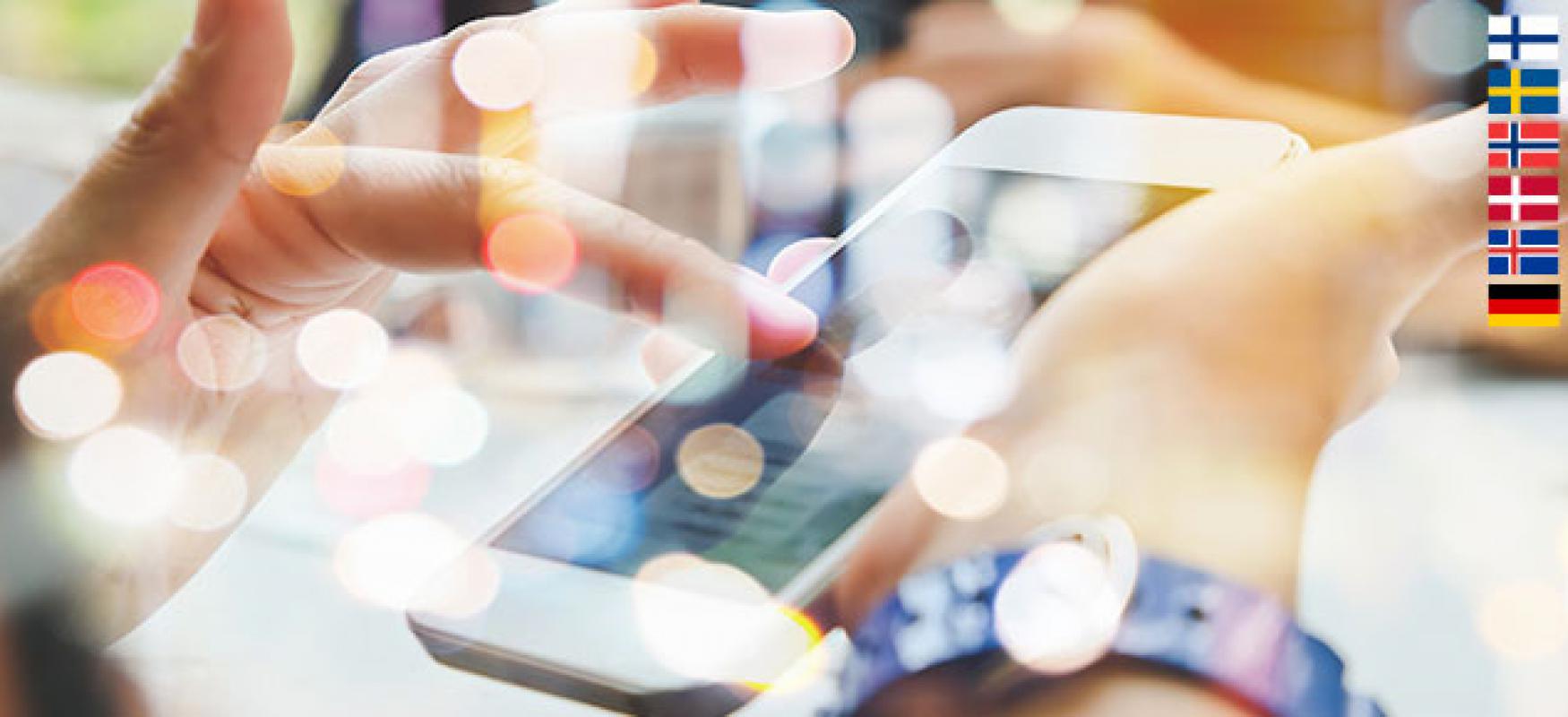 A photo with a lot of lense flare showing a person using a smartphone. Flags of the five Nordic countries and Germany is in the right corner.